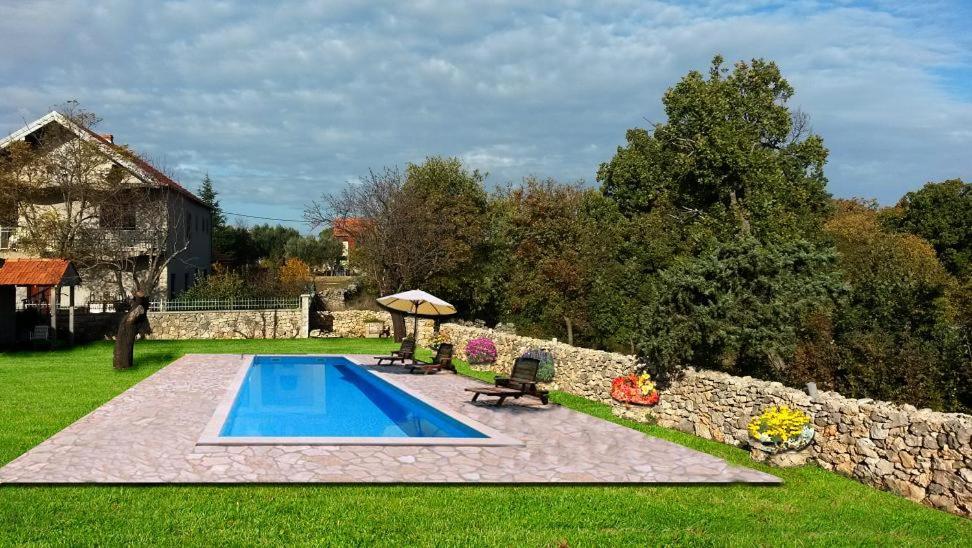 a swimming pool in a yard next to a stone wall at Agrotourism Galic Krka in Drinovci