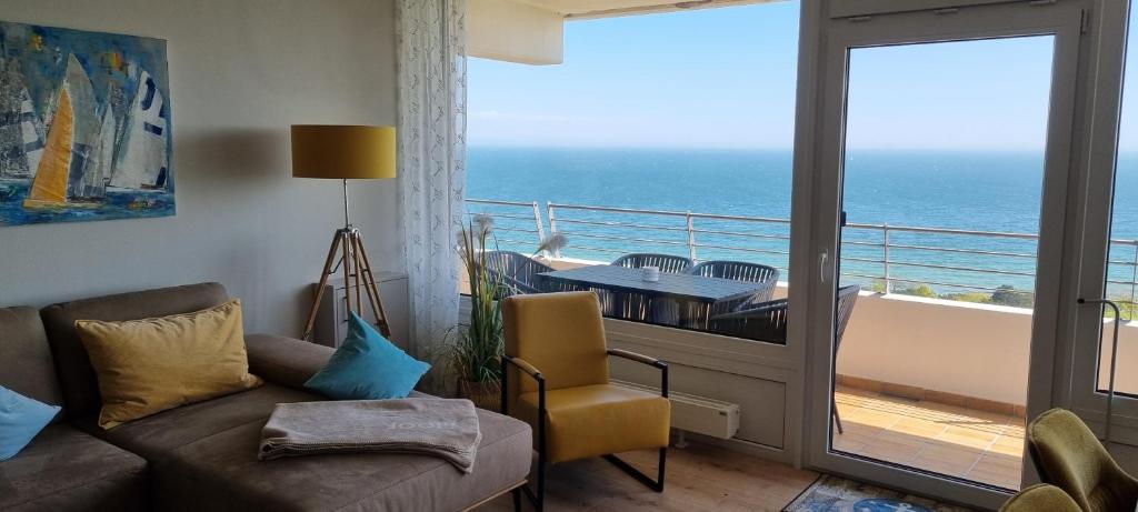 a living room with a couch and a balcony with the ocean at Himmel & Meer Suite in Timmendorfer Strand