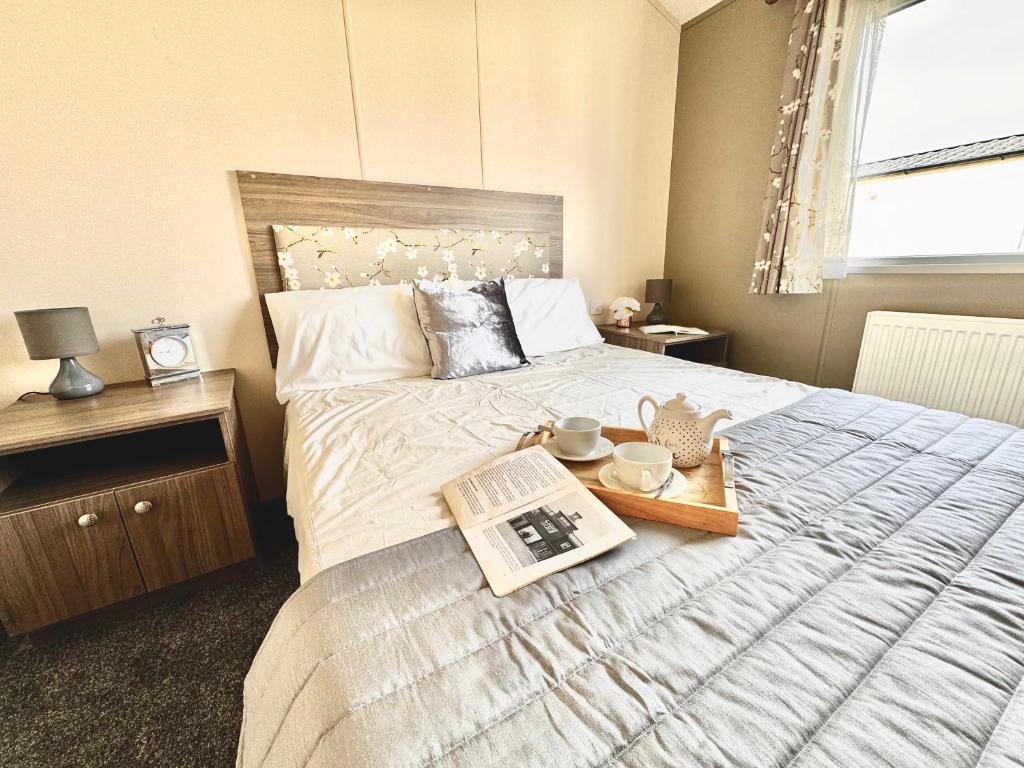 a bedroom with a bed with a tray with a book at Seaside Escape - Parkdean Resort Camber Sands in Camber