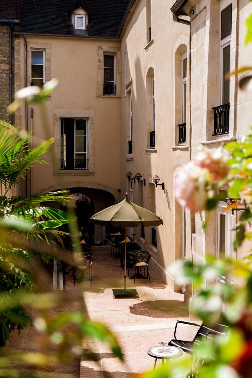 an outdoor patio with an umbrella and chairs and tables at Hôtel La Particulière in Caen