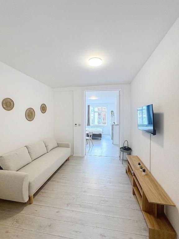 a white living room with a couch and a table at Spacieux appartement une chambre in Brussels