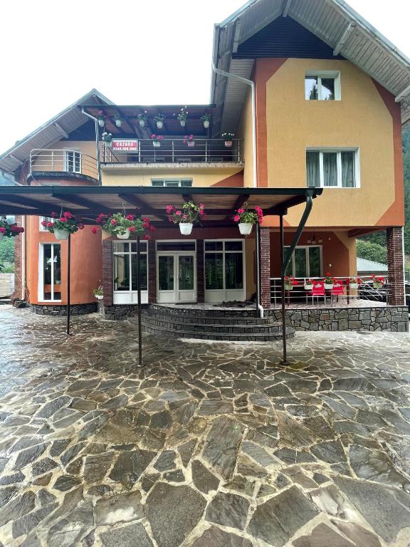 a building with a stone ground in front of it at Pensiunea Pe drumuri de munte in Borca