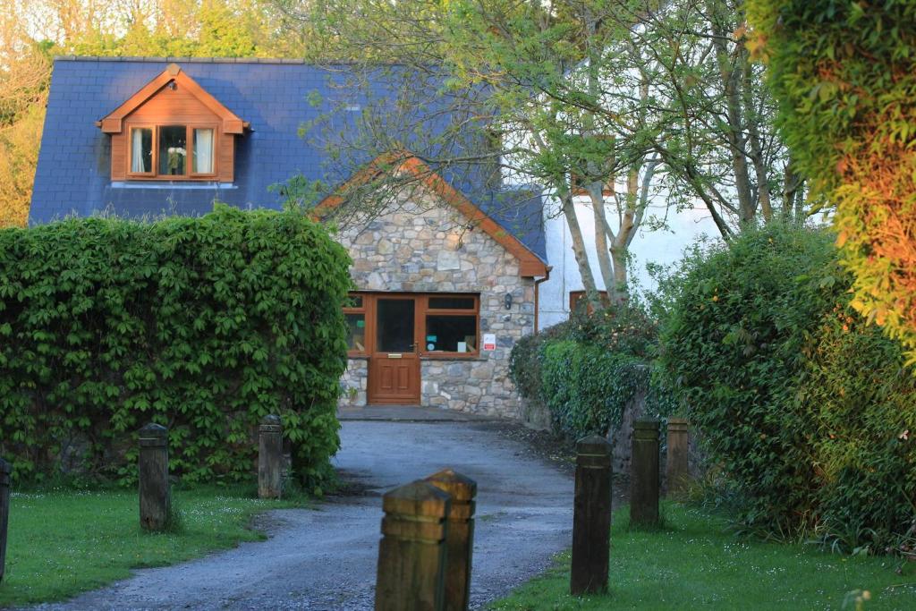 a house with a blue roof and a driveway at Ballas Farm Country Guest House in Bridgend