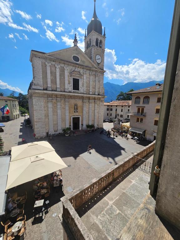 Un edificio antiguo con una torre de reloj con un paraguas. en GardaInn Palazzo Nuovo, en Arco