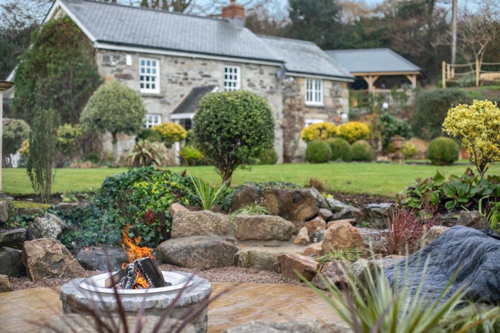 a garden with a stone house and a fire pit at Rose Cottage in Saint Hilary