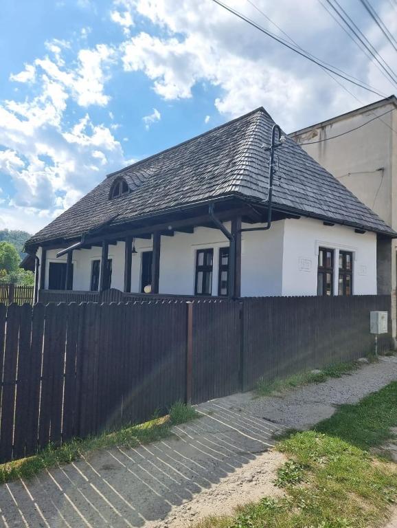 a white house with a black roof and a fence at Casuța din Domnești in Domneşti