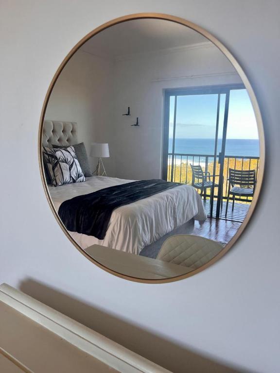 a mirror reflecting a bedroom with a bed and a balcony at Bo-den-See Guesthouse in Great Brak River