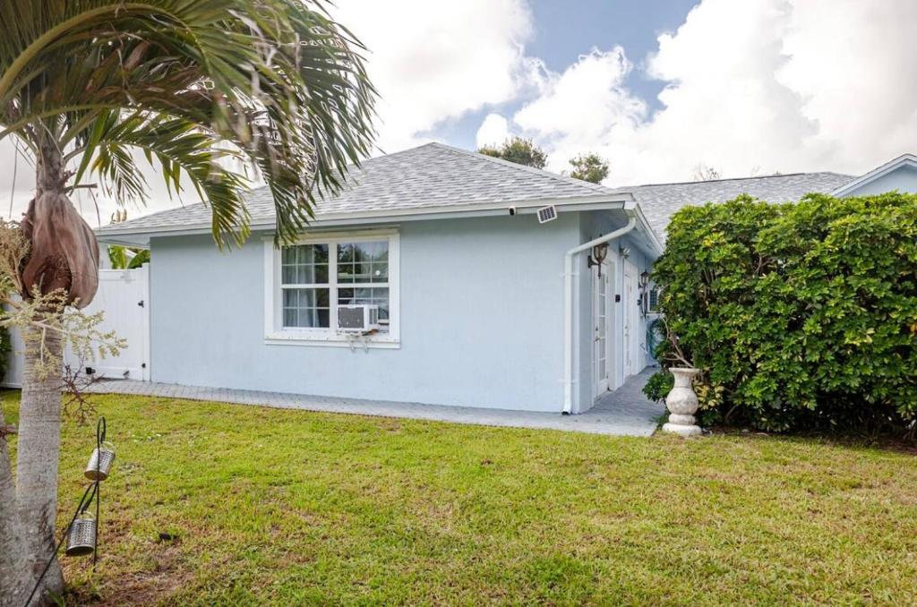 a white house with a palm tree in a yard at Brand new studio apartment in Vero Beach