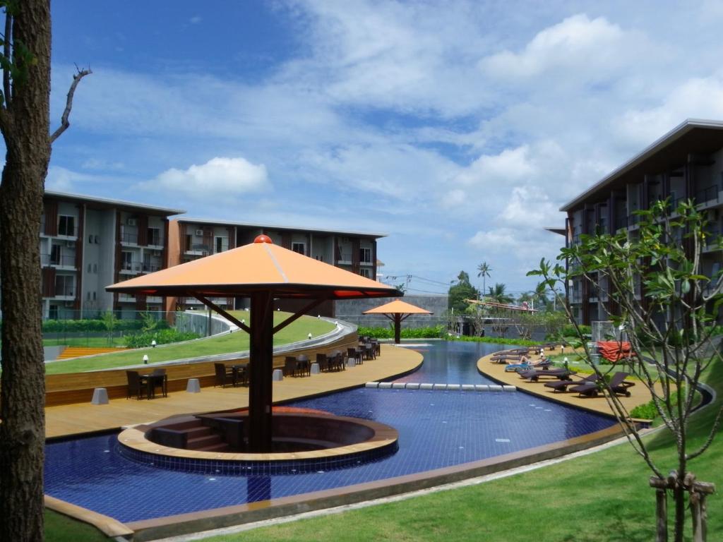 an outdoor pool with an umbrella and tables and chairs at Replay Condo Studio Room in Bangrak Beach