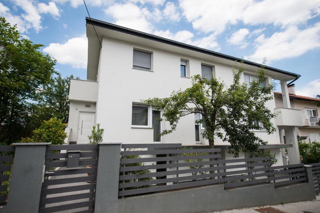 una casa blanca con una valla delante en New Apartments, en Zagreb
