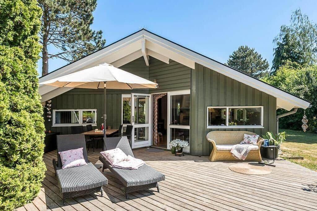 patio z krzesłami i parasolem na tarasie w obiekcie R968-Rodvig-Skovstumperne-8 w mieście Rødvig