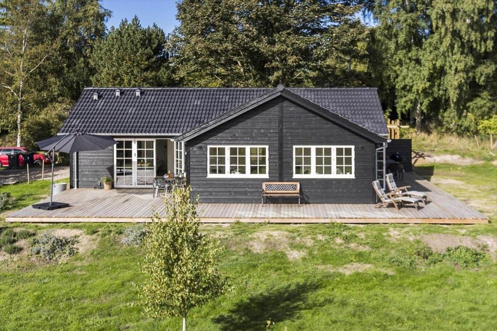 una pequeña casa negra con terraza de madera en 3011-Stege-Straektovet-18, en Stege