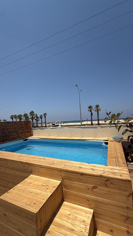 a large swimming pool with a wooden deck with at Sea side Ashdod יא in Ashdod