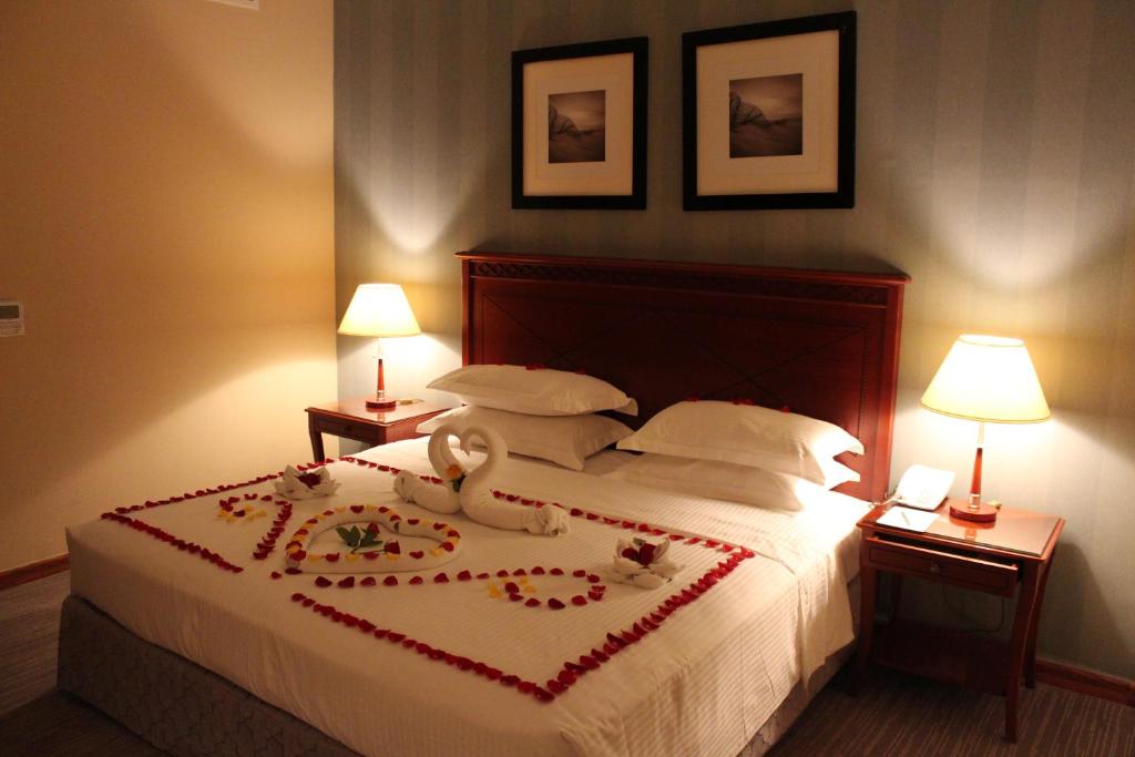 Manazel Al Diafa Serviced Apartments في الرياض: غرفة نوم عليها سرير وبجعة