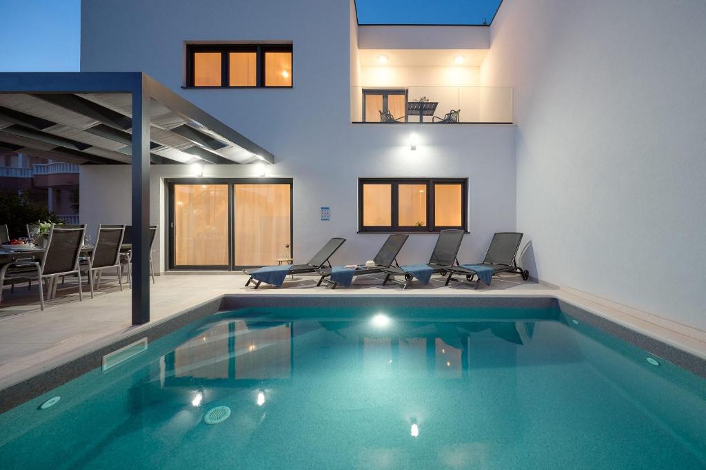 a house with a swimming pool with chairs and a table at Villa Ante Vodice in Vodice