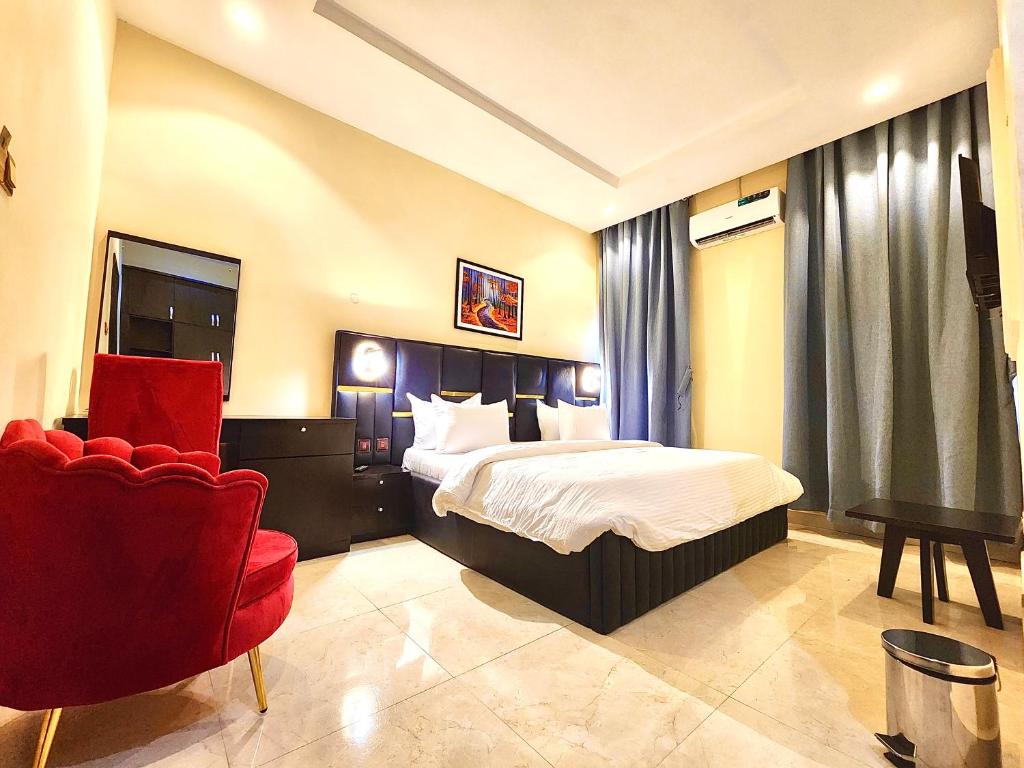 a hotel room with a bed and a red chair at Buddiez Hotel & Resort in Enugu