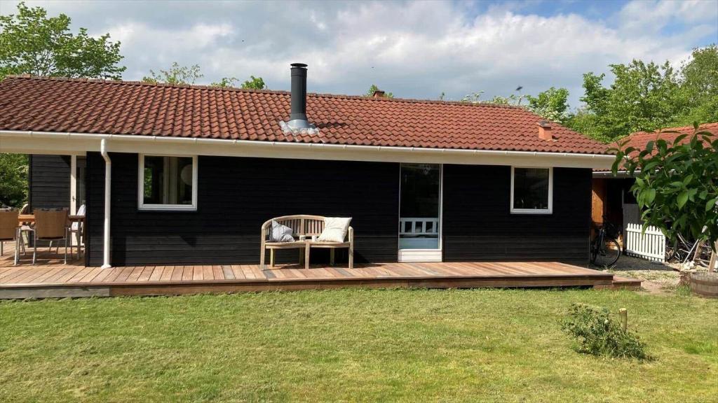 a black house with a deck with a chair on it at R963-Rodvig-Skovstumperne-3 in Rødvig