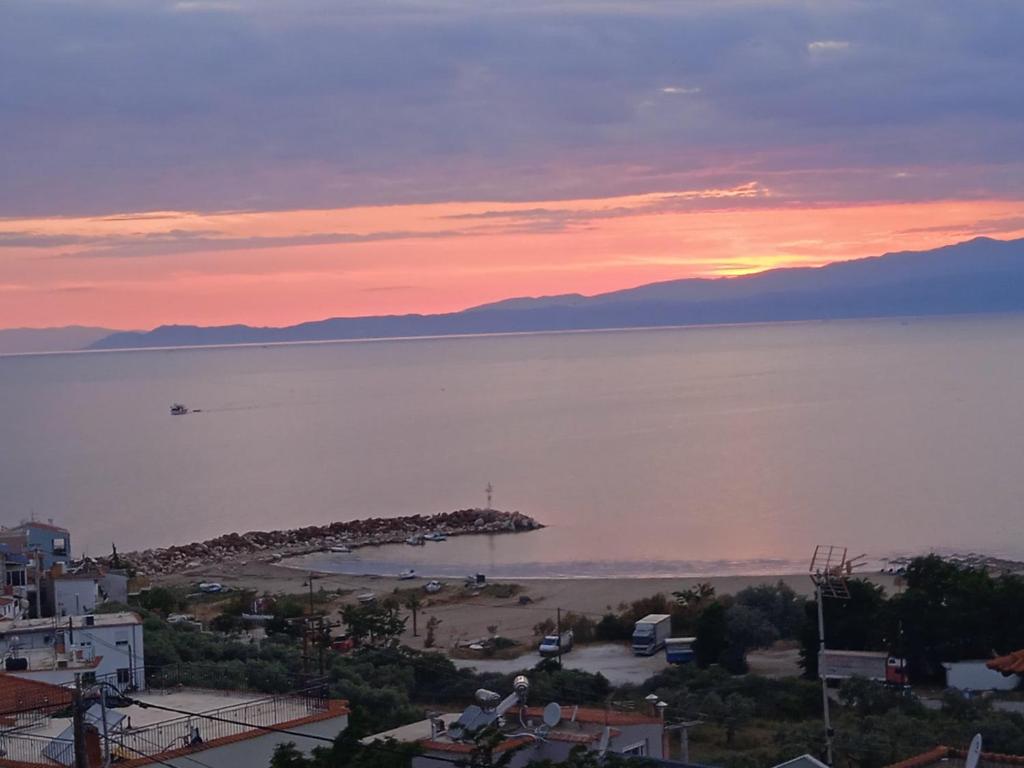 a sunset over a body of water with a small island at Alexandras Villa in Skala Marion