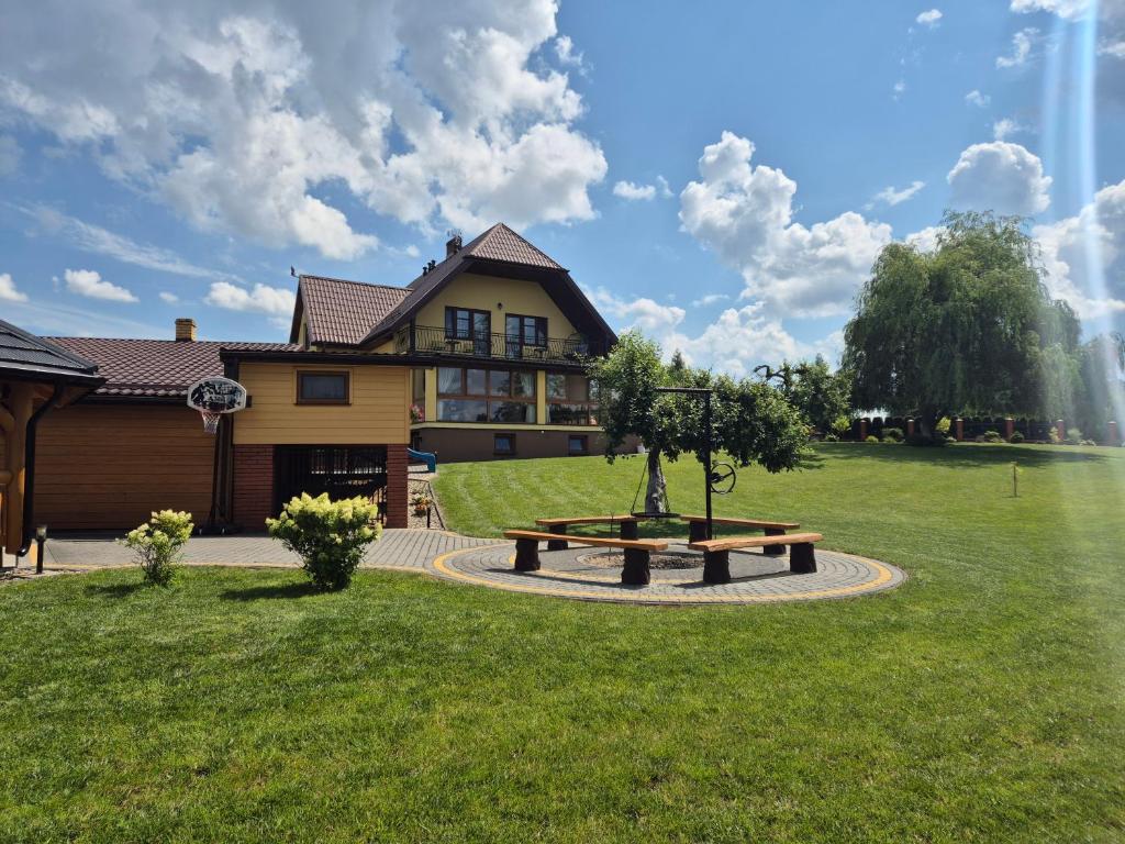 a park with a bench in front of a house at Agroturystyka Żubrówka in Żubrówka