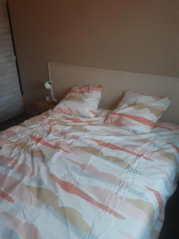 an unmade bed with a red and white comforter at 1er etage d'une maison in Sorgues