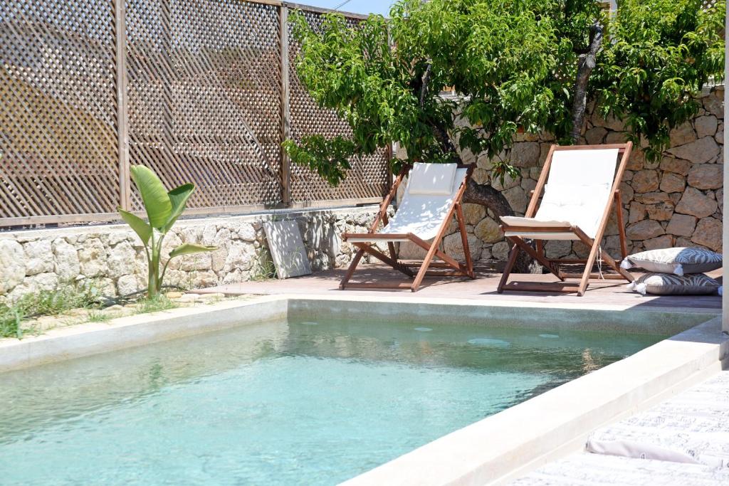 two chairs sitting next to a swimming pool at Village Escape House by CorfuEscapes in Lefkimmi