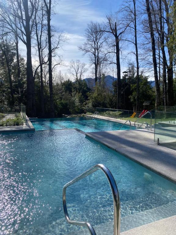 a swimming pool with a metal handrail in the water at Acogedor departamento de lujo in Pucón