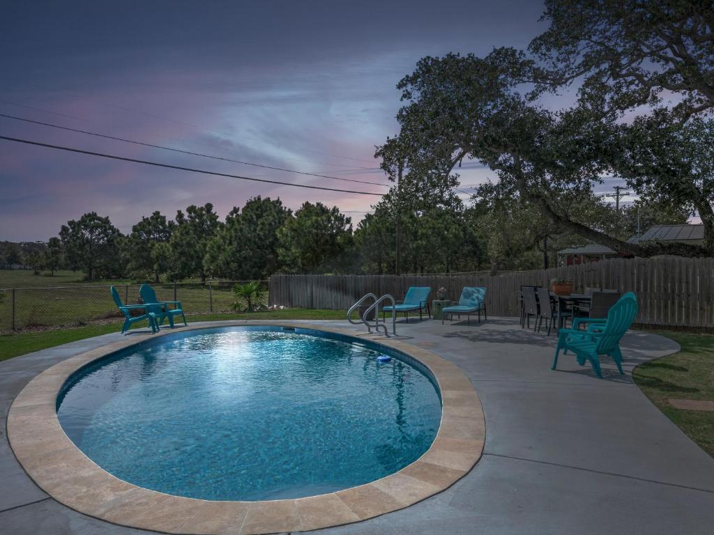 a swimming pool with blue chairs and a table at The Sea Glass House in Rockport