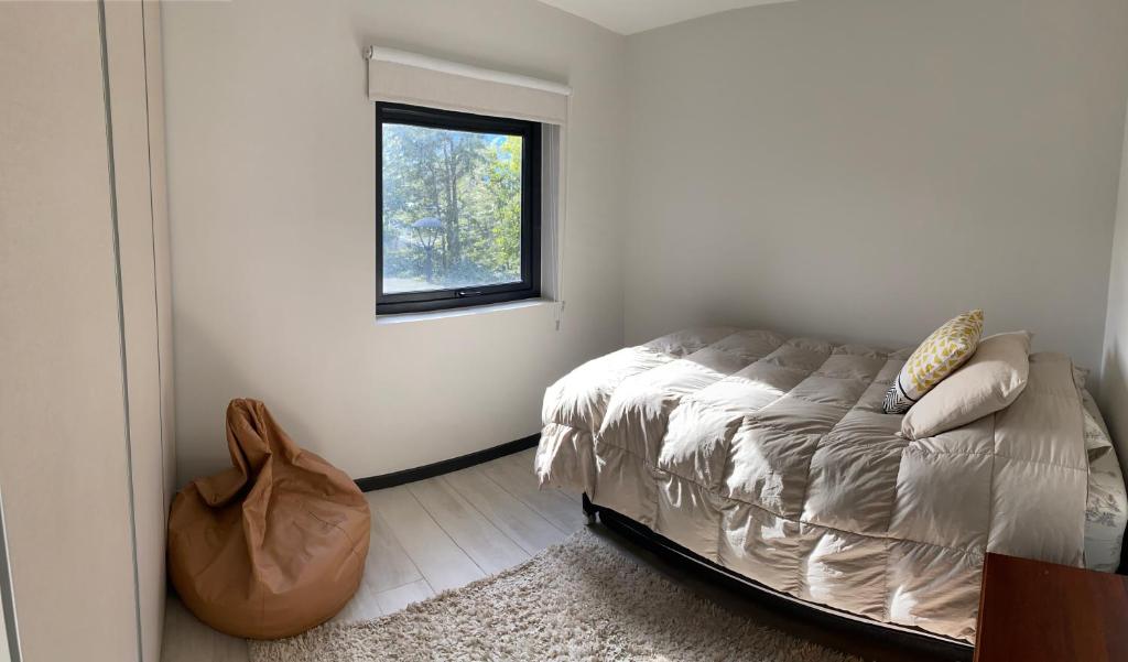 a bedroom with a bed and a window at Acogedor departamento de lujo in Pucón