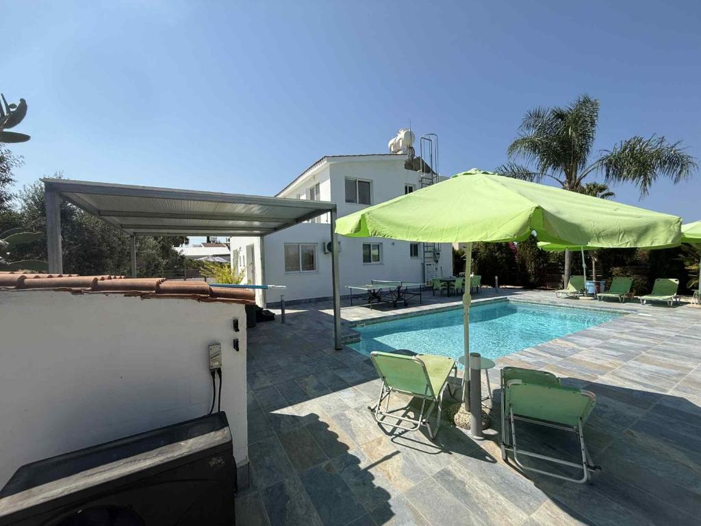 una piscina con due sedie e un ombrellone verde di Villa Coralia Gardens 1km From Coral Bay Beach a Coral Bay