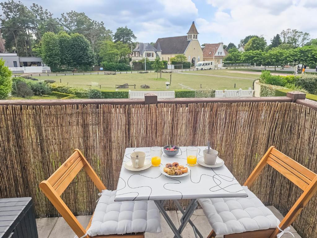 uma mesa branca e cadeiras com uma tigela de comida na varanda em F2 cosy avec balcon em Merville-Franceville-Plage