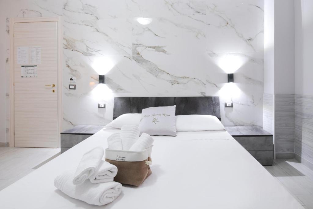 a white bedroom with a large bed with towels on it at NICOLE LUXURY ROOMS in Fondi