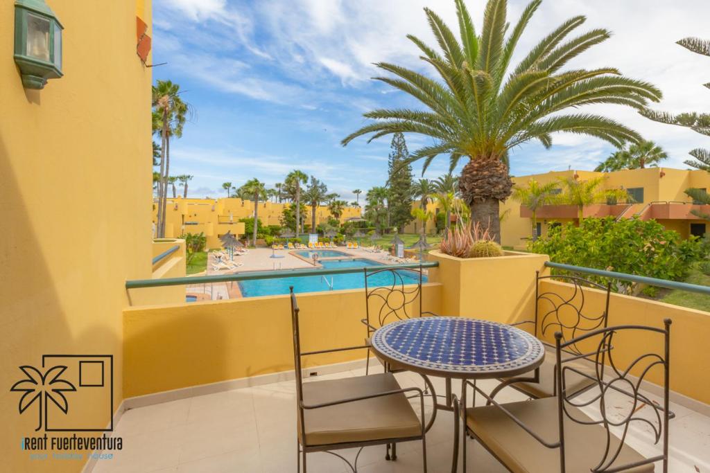 ein Balkon mit Tisch und Stühlen und ein Pool in der Unterkunft Palmira Sea View and Lobos Island iRent Fuerteventura in Corralejo