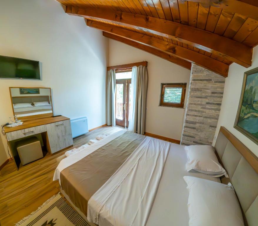 een slaapkamer met een groot bed en een open haard bij Sofra Kelmendit in Tamarë