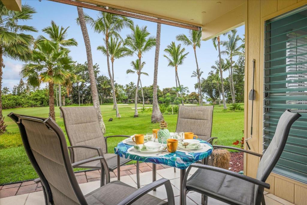 a table and chairs on a porch with palm trees at Keauhou Palena 901 in Kailua-Kona