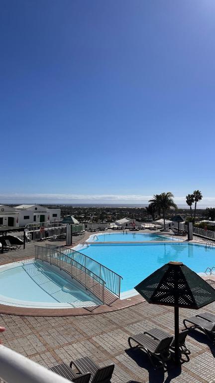 a large swimming pool with chairs and an umbrella at Golden Views Apartment in San Bartolomé