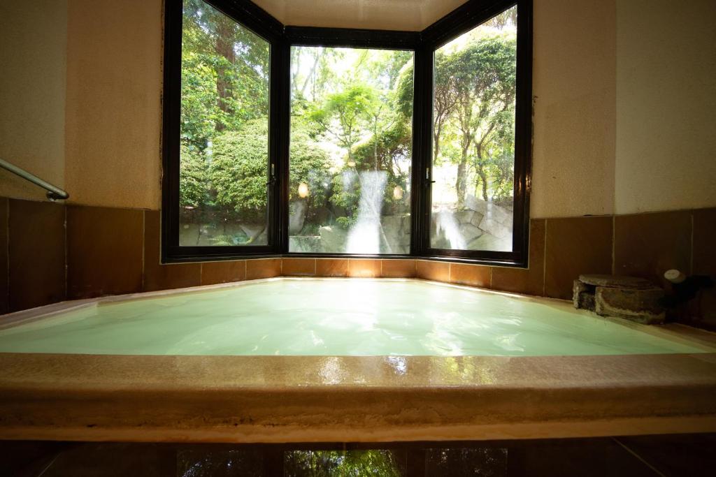 un bain à remous dans une pièce avec deux fenêtres dans l'établissement Ryokan Kiritani Hakoneso, à Hakone