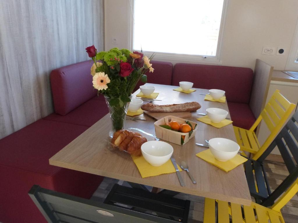 Una mesa con un jarrón de flores y comida encima. en Mobilhome 4 chambres 8 places, en Erquy