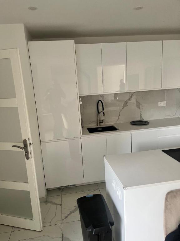 a kitchen with white cabinets and a sink at Emmanuel INN 3 in Drancy