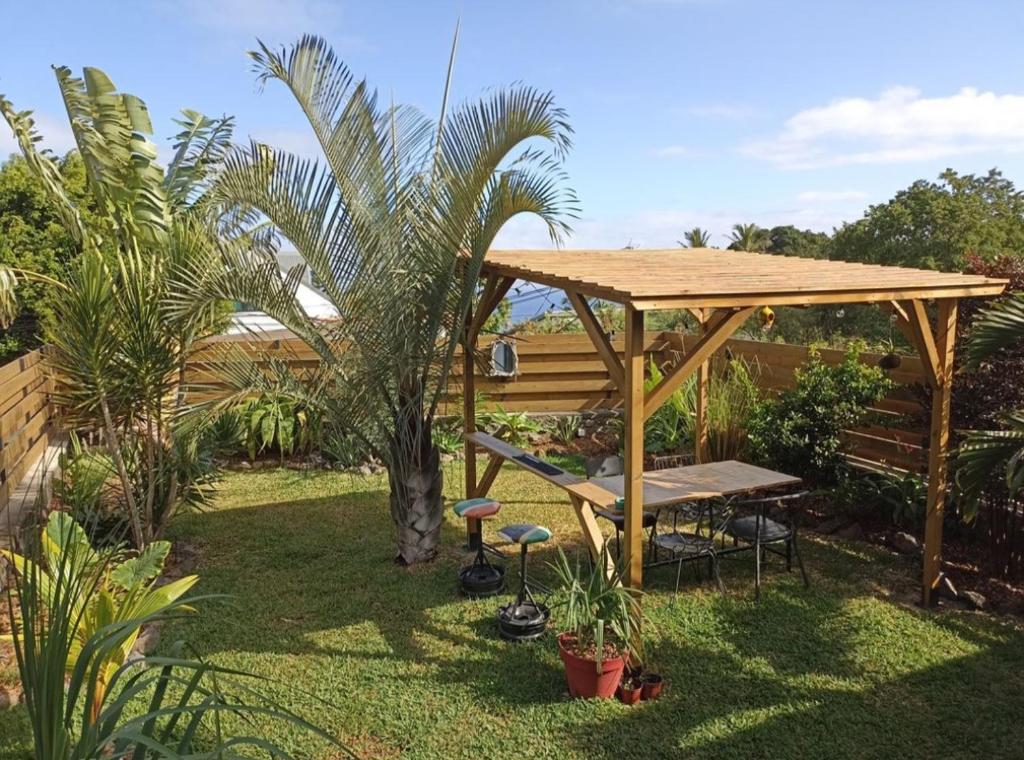 un gazebo in legno con una panca e una palma di Maison familiale Saint Leu a Saint-Leu
