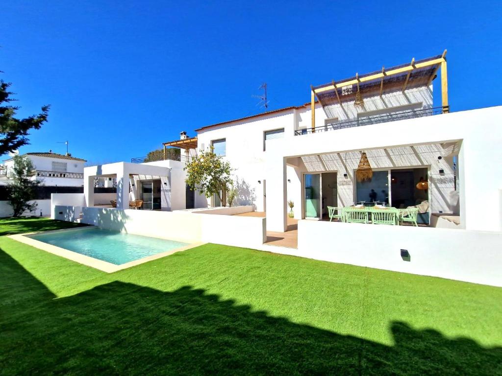 een wit huis met een gazon en een zwembad bij Apartaments Gorgot in Empuriabrava