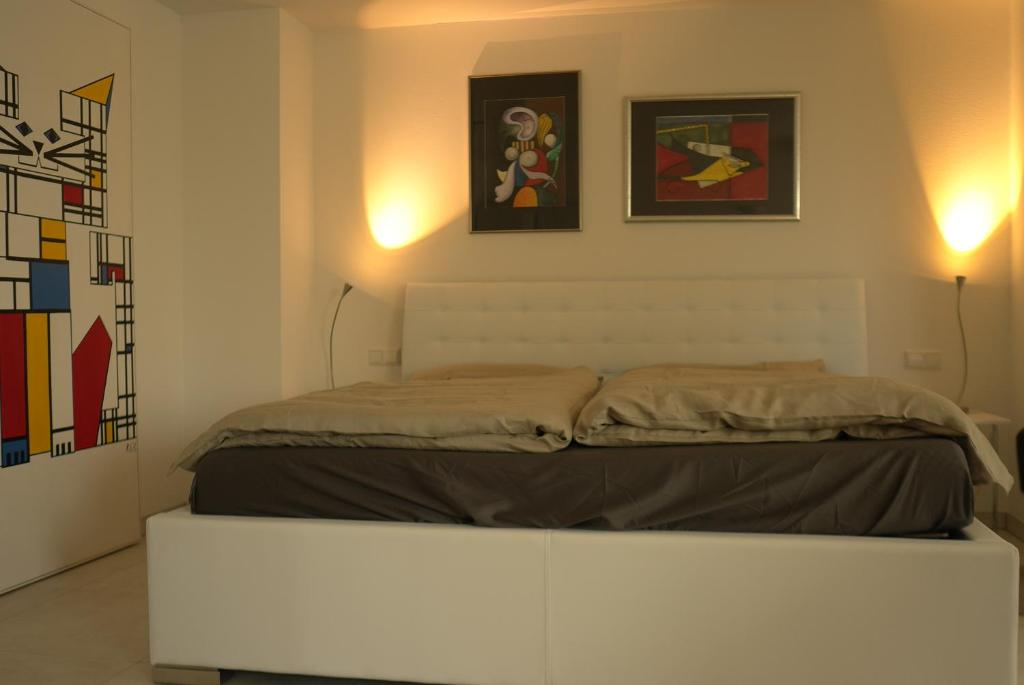 ein Schlafzimmer mit einem Bett und zwei Gemälden an der Wand in der Unterkunft Villa Adagio in Badenweiler