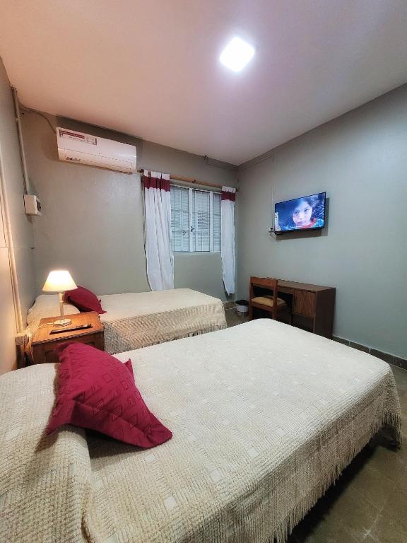 a bedroom with two beds and a tv on the wall at Cómo en casa, cerca de todo, amplio 100m2 in San Miguel de Tucumán