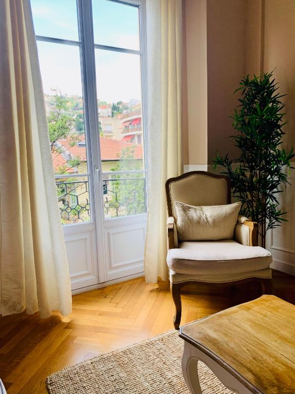 un salon avec une chaise et une grande fenêtre dans l'établissement Appartement Nice Chic Centre Libération, à Nice