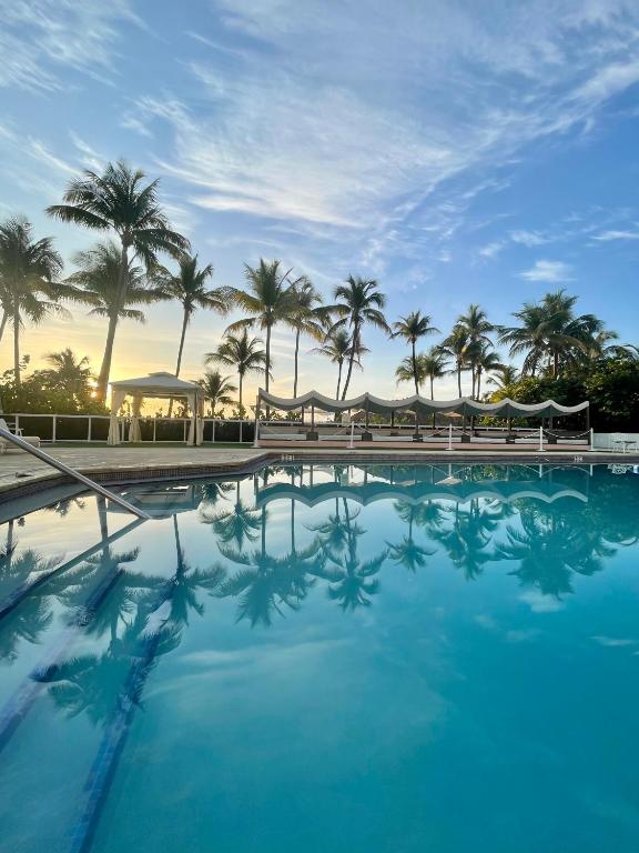 a swimming pool with palm trees in the background at Seacoast Suites on Miami Beach in Miami Beach