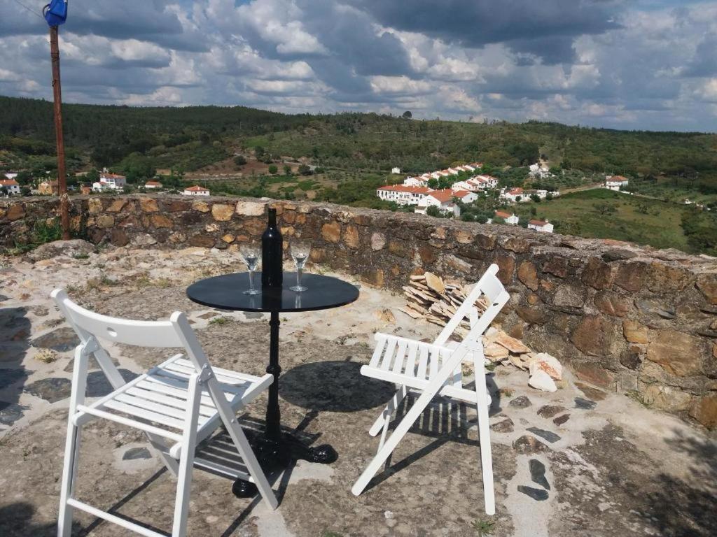 two white chairs and a table on a stone wall at Casas de Alegrete - Castelo by Portus Alacer in Alegrete