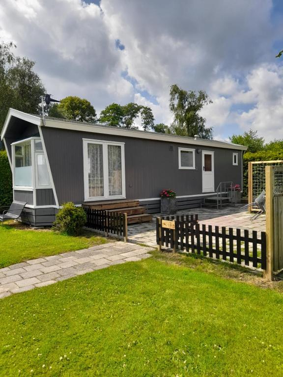 a small grey house with a wooden fence at Chalet B2 in Westergeest