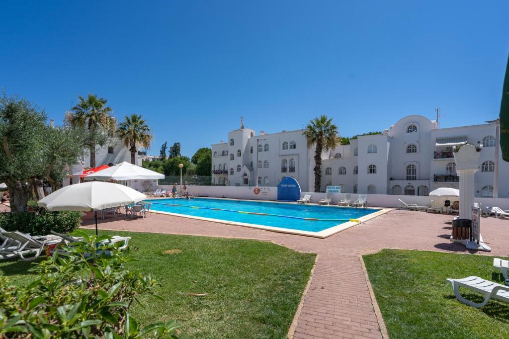 a swimming pool in the middle of a resort at Elegant Flat with Pool & Balcony by HostWise in Tavira