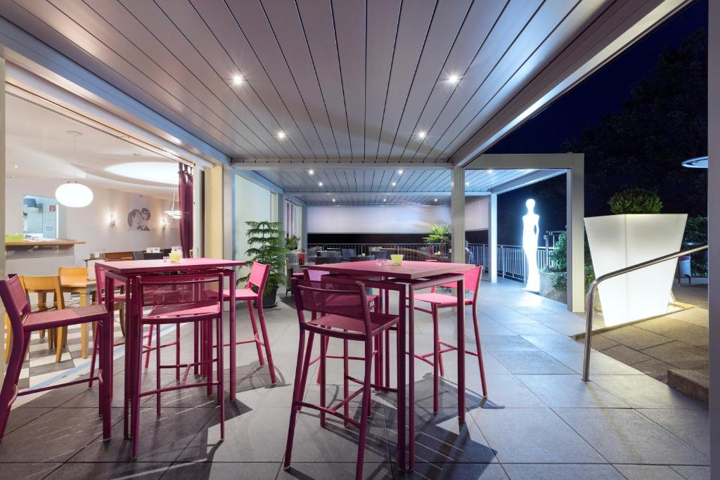 ein Restaurant mit roten Tischen und Stühlen auf einer Terrasse in der Unterkunft Hôtel Bellevue in Pruntrut