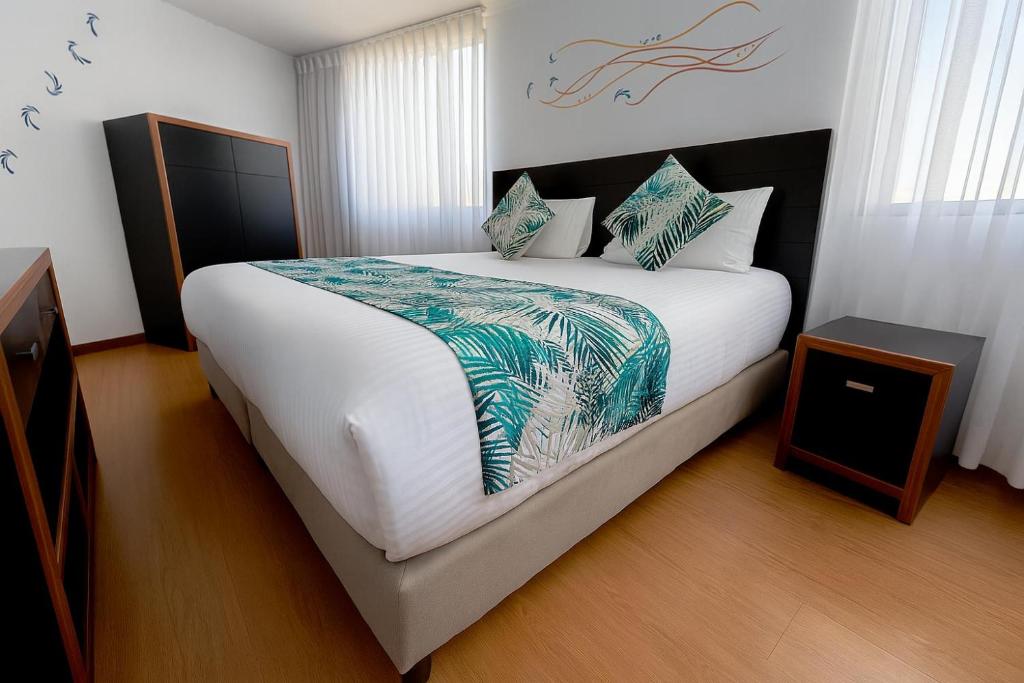 a bedroom with a large bed with white sheets and pillows at Hotel Benidorm in Manizales