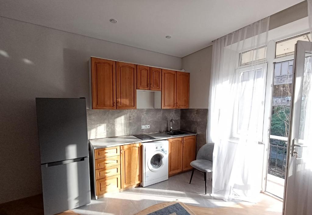 a kitchen with wooden cabinets and a white refrigerator at Sweet Home Mergelyan in Yerevan